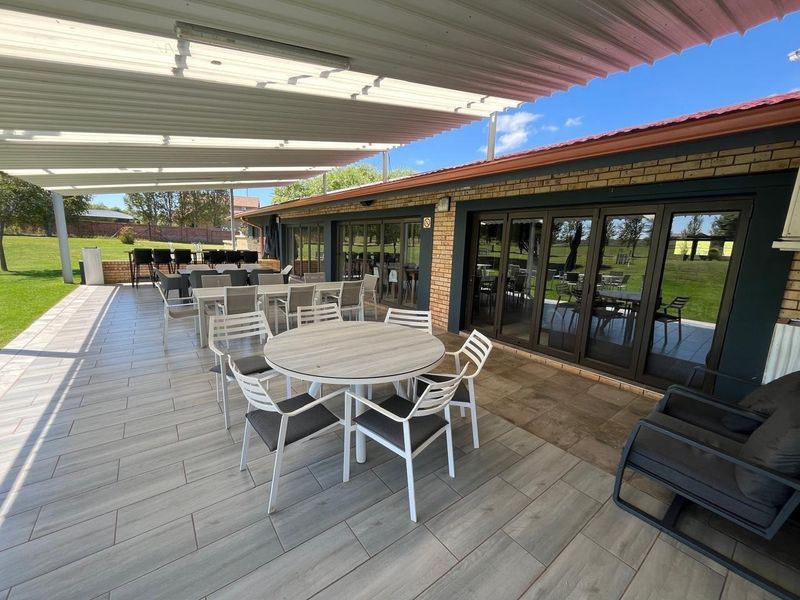 Spacious covered patio area featuring modern tiled flooring, a corrugated metal roof, and large aluminium stacker doors providing seamless indoor-outdoor flow.