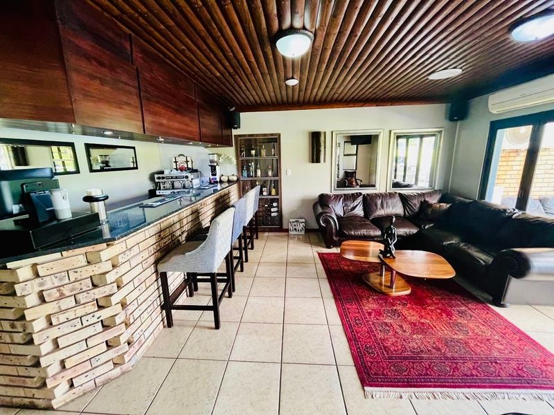 A well-appointed bar area featuring a brick-based bar with granite countertop, timber slat ceiling, and integrated display shelving, creating a cozy entertainment space.