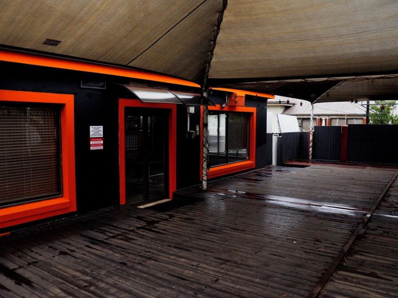 Covered outdoor patio area featuring timber decking, shade sail protection, and secure access points, suitable for commercial use or outdoor seating.