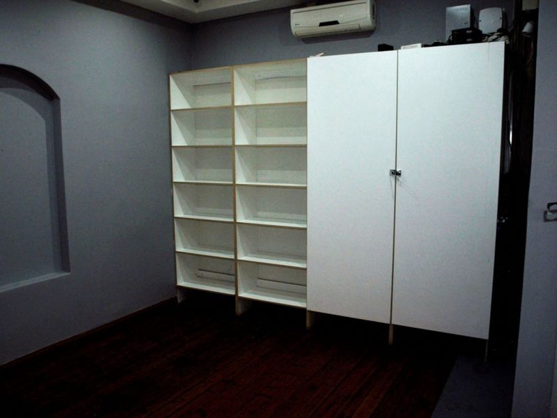 An office space featuring dark timber flooring, a recessed wall niche, and extensive built-in white cabinetry and shelving units.