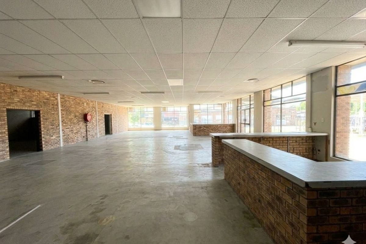 Spacious open-plan commercial area featuring exposed brick walls, concrete flooring, and a built-in brick service counter, suitable for retail or office use.