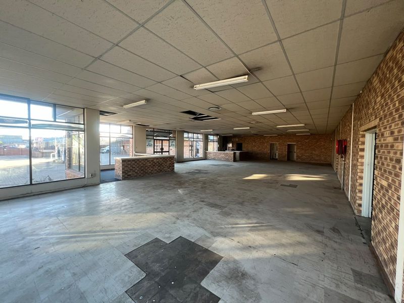 Spacious open-plan commercial interior featuring exposed brick walls, large windows, and built-in brick service counters, suitable for retail or office use.