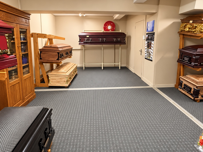 A well-maintained commercial showroom space featuring neutral walls, carpeted flooring, and built-in display cabinetry for funeral products.