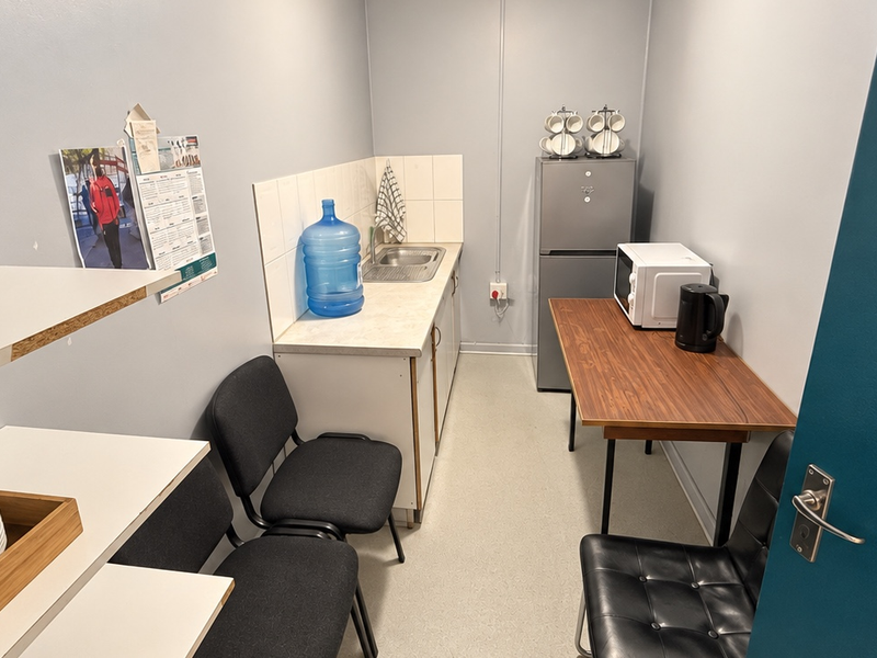 A compact kitchenette featuring a single sink, tiled splashback, and base cabinetry, providing essential utility space for a business environment.