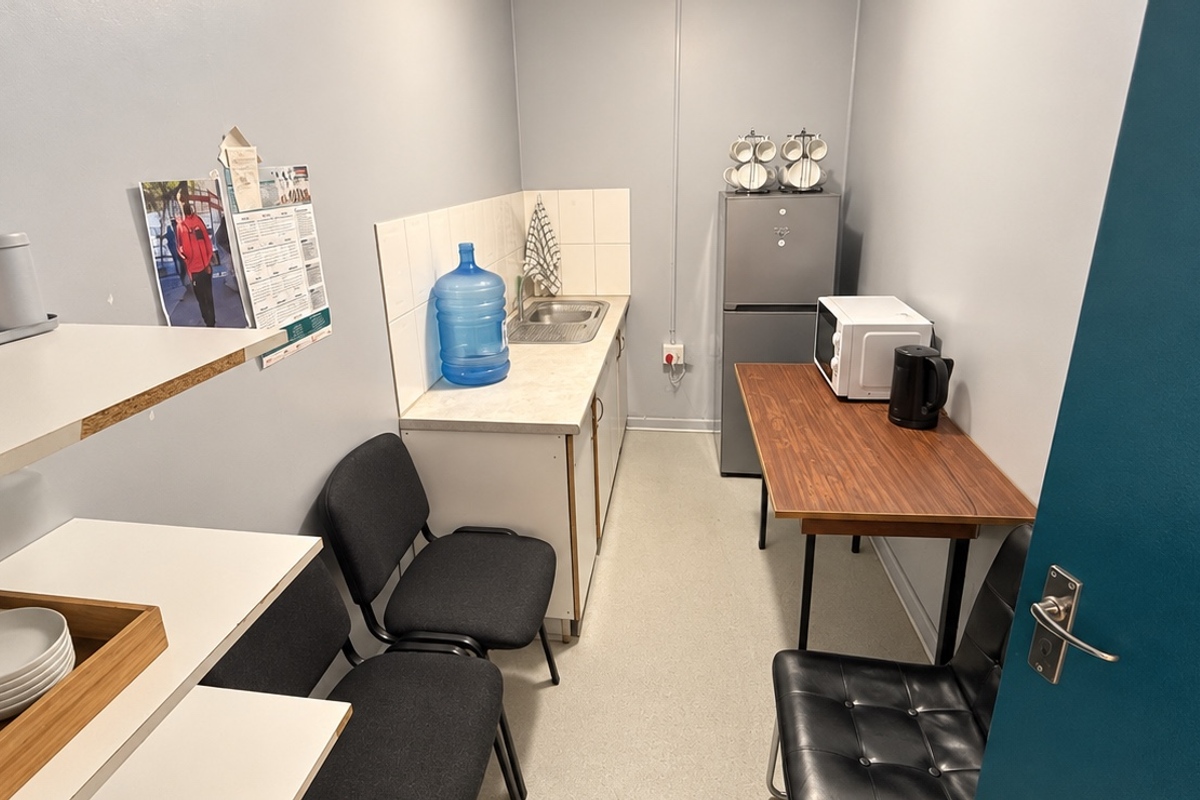 A compact kitchenette featuring a single sink, tiled splashback, and base cabinetry, providing essential utility space for a business environment.