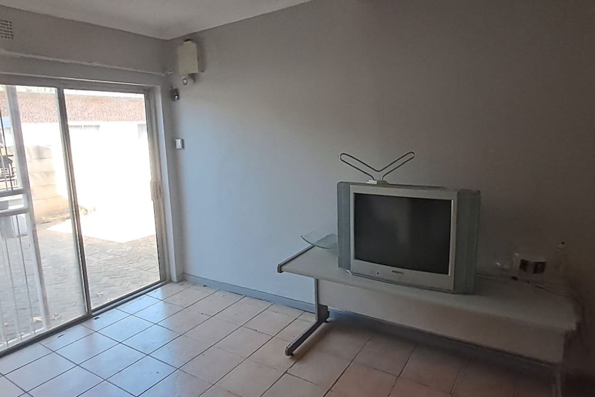 A living room featuring tiled flooring and a large sliding glass door providing access to the exterior area.