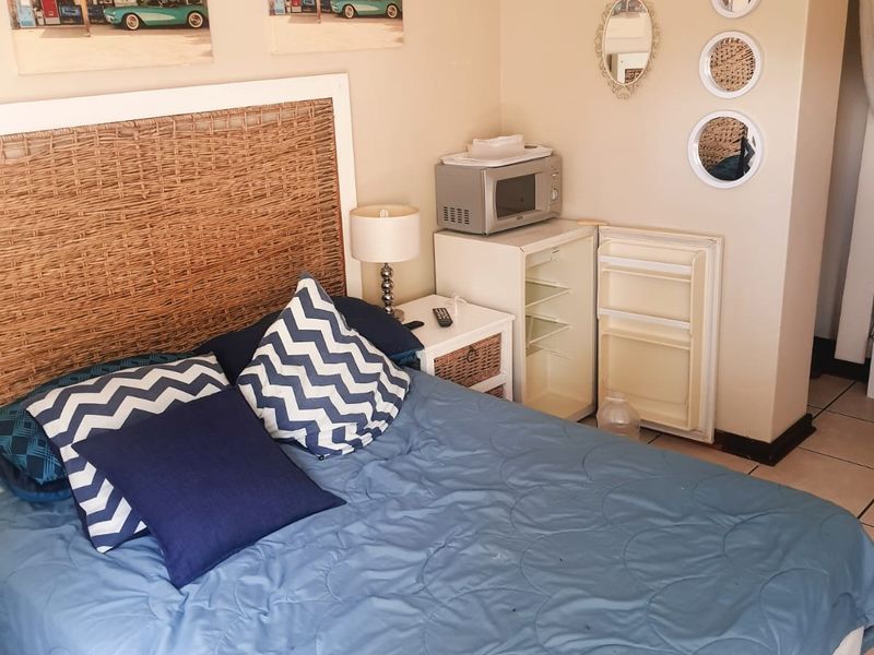 A bedroom featuring tiled flooring and neutral wall finishes, currently configured with a bed and small kitchenette-style appliance area.
