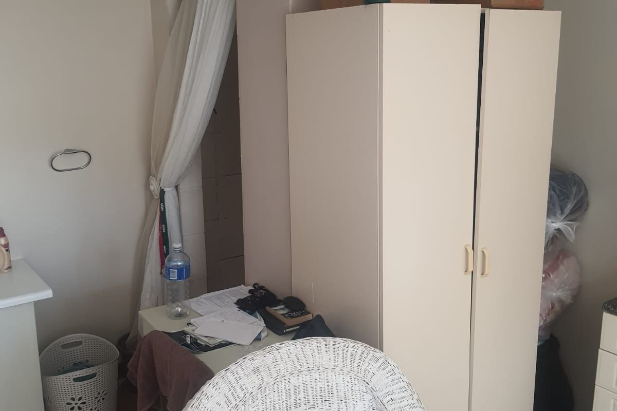 A bedroom space featuring a built-in cupboard, currently used for storage and personal items.