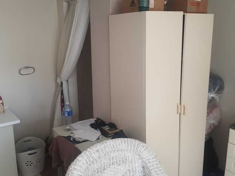 A bedroom space featuring a built-in cupboard, currently used for storage and personal items.