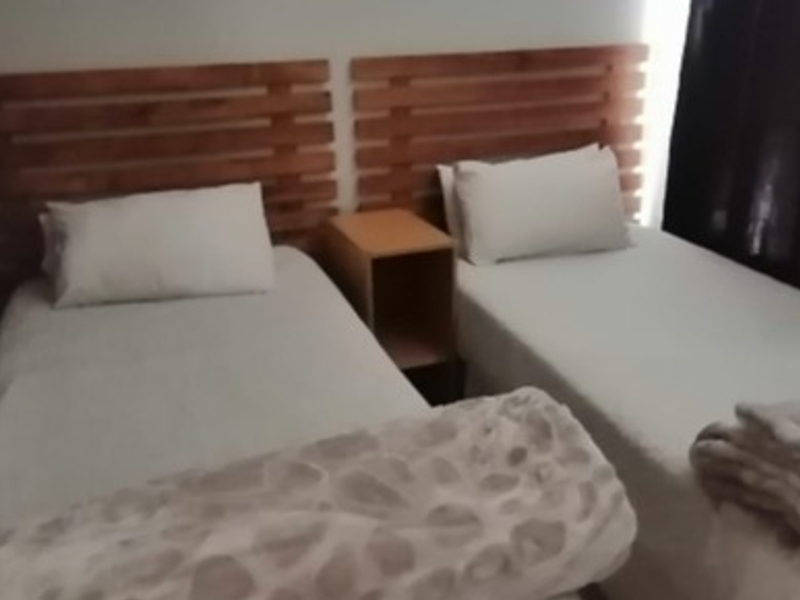 A bedroom featuring two single beds with wooden headboards and a central bedside table.