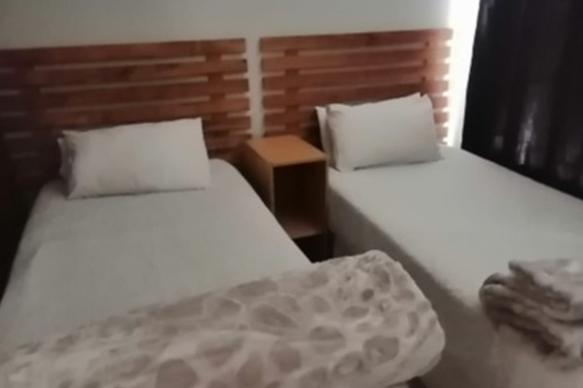 A bedroom featuring two single beds with wooden headboards and a central bedside table.
