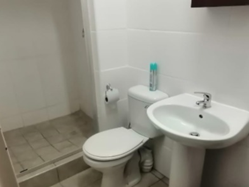 A functional bathroom featuring a pedestal basin, toilet, and a separate shower enclosure with tiled finishes throughout.