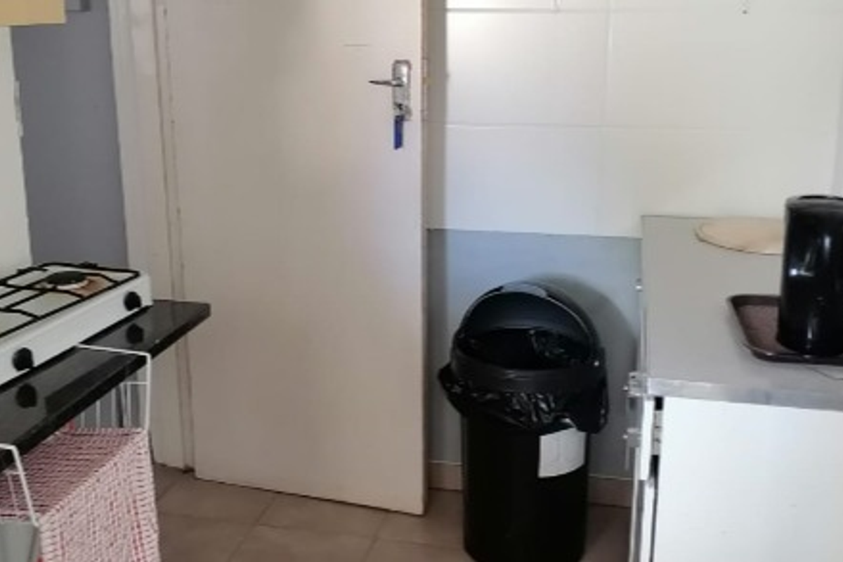 A compact kitchen area featuring a gas hob, tiled splashbacks, and basic cabinetry, requiring cosmetic updates to modernize the space.