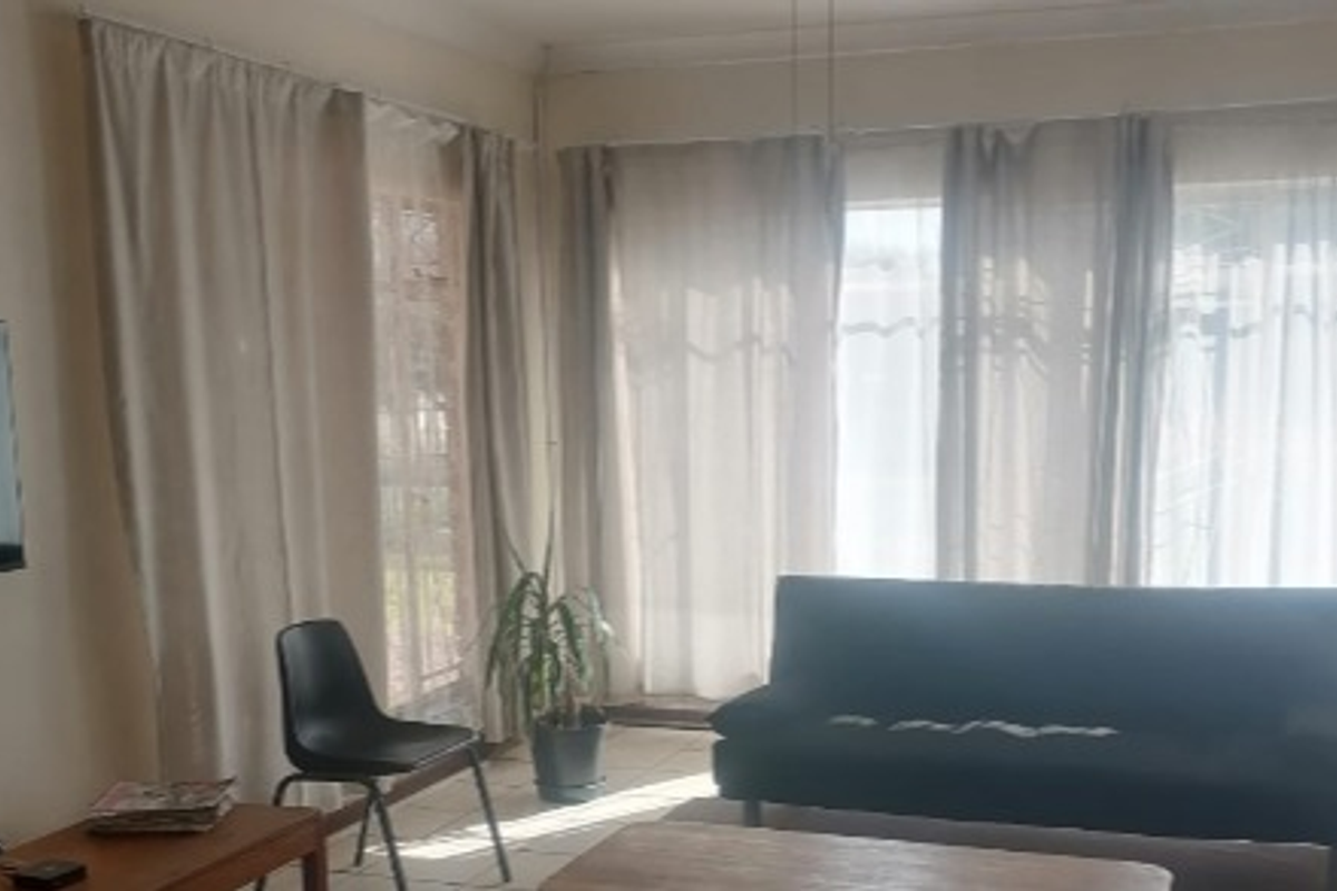 A living room area featuring tiled flooring and large windows that allow for natural light.