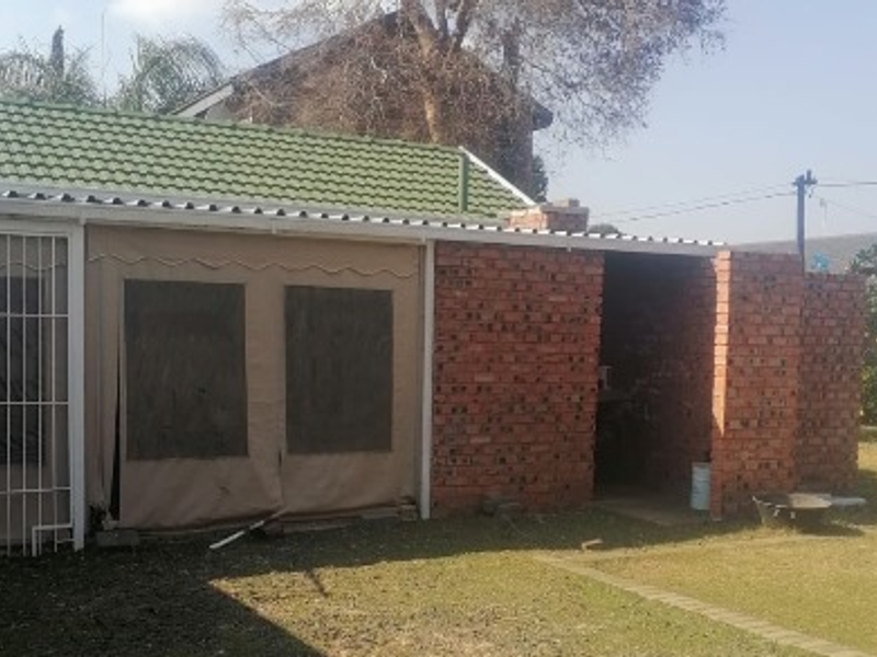 Rear view of the property featuring a brick structure with a tiled roof and a covered patio area with canvas enclosures.