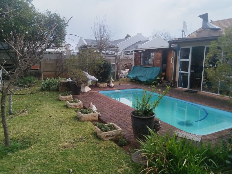 Outdoor pool area featuring a swimming pool with brick paving surround, adjacent to the main building structure with sliding glass door access.