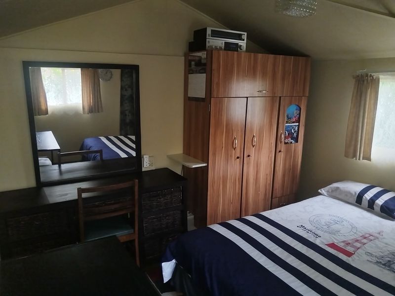 A bedroom featuring a sloped ceiling and a built-in wooden wardrobe, providing functional storage space within the room.