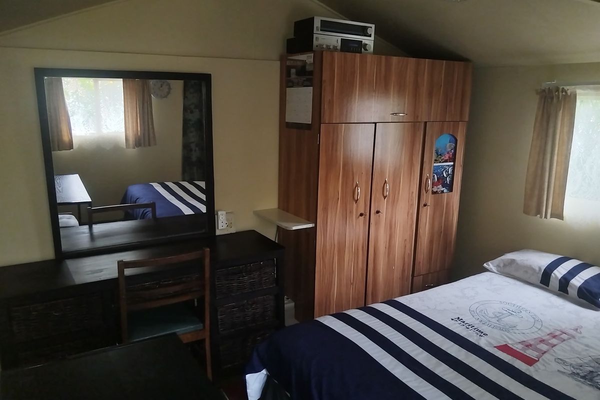 A bedroom featuring a sloped ceiling and a built-in wooden wardrobe, providing functional storage space within the room.