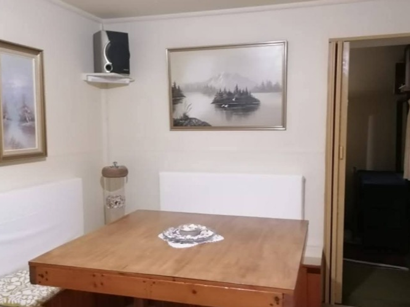 A compact dining area featuring a folding door leading to an adjacent room, with dated wall finishes and basic interior structure.