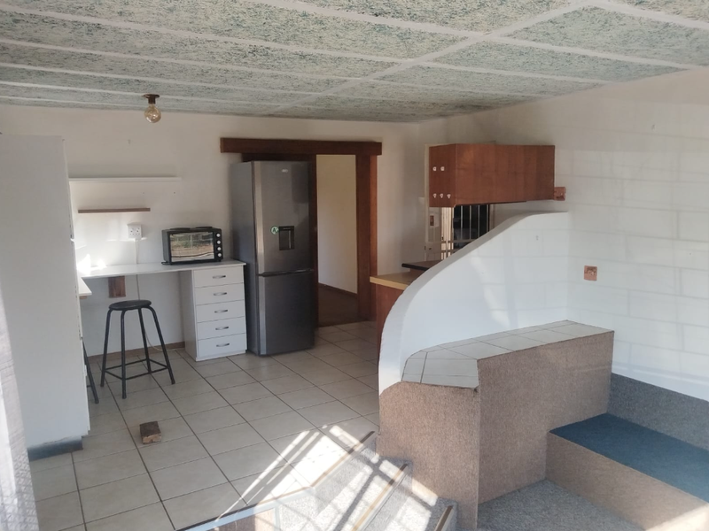 A functional kitchen area featuring tiled floors, built-in cabinetry, and a split-level layout with a carpeted step.