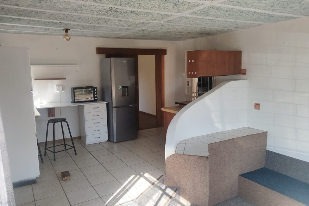 A functional kitchen area featuring tiled floors, built-in cabinetry, and a split-level layout with a carpeted step.