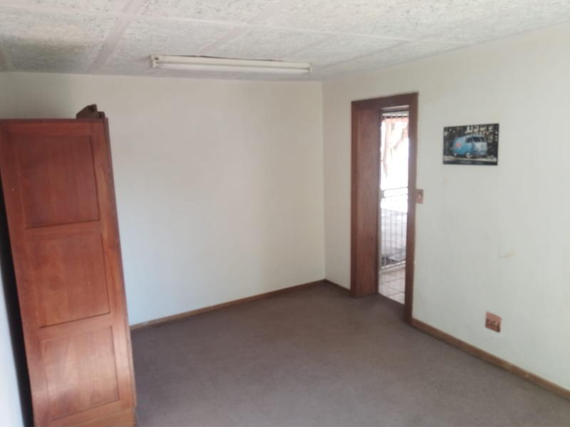 A bedroom featuring carpeted flooring, textured ceiling tiles, and a wooden door frame leading to an adjacent space.