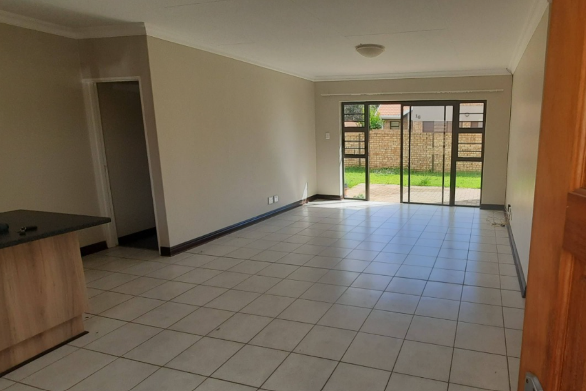 Spacious open-plan living area featuring neutral walls, tiled flooring, and a sliding glass door providing direct access to the rear garden.