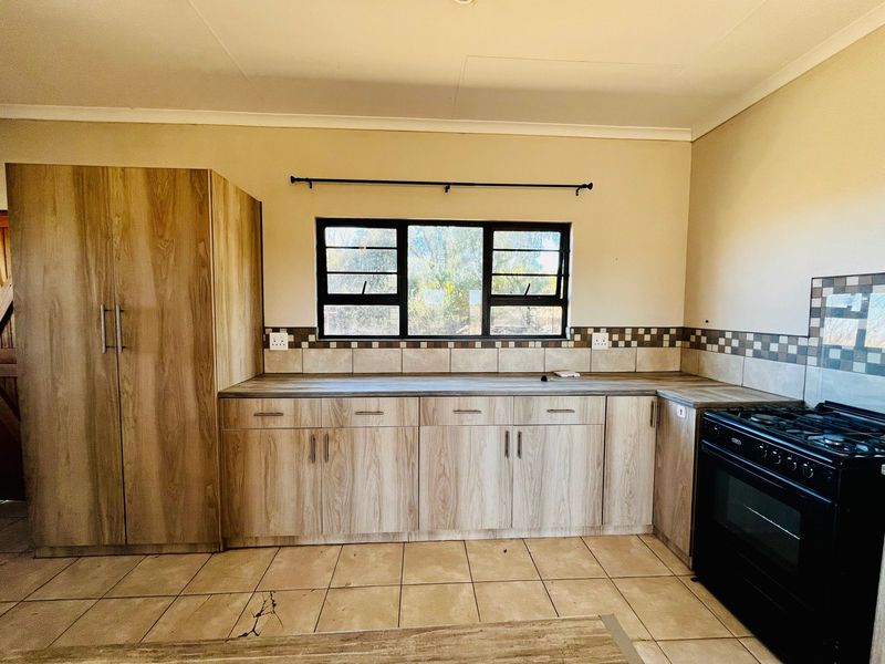 A functional kitchen featuring wood-look laminate cabinetry, tiled backsplash, and a freestanding oven, offering a clean and practical workspace.