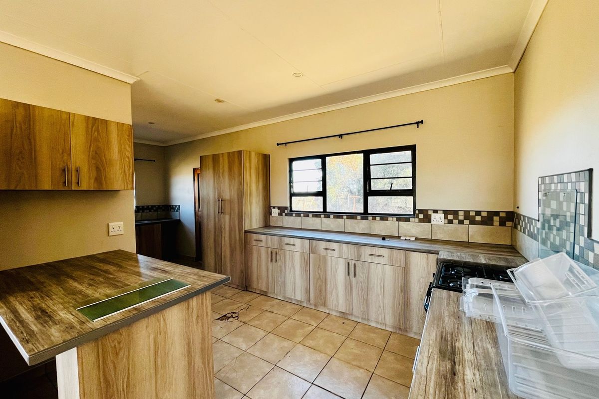 A functional kitchen featuring wood-look laminate cabinetry, tiled countertops, and a built-in gas hob, offering a clean and practical workspace.