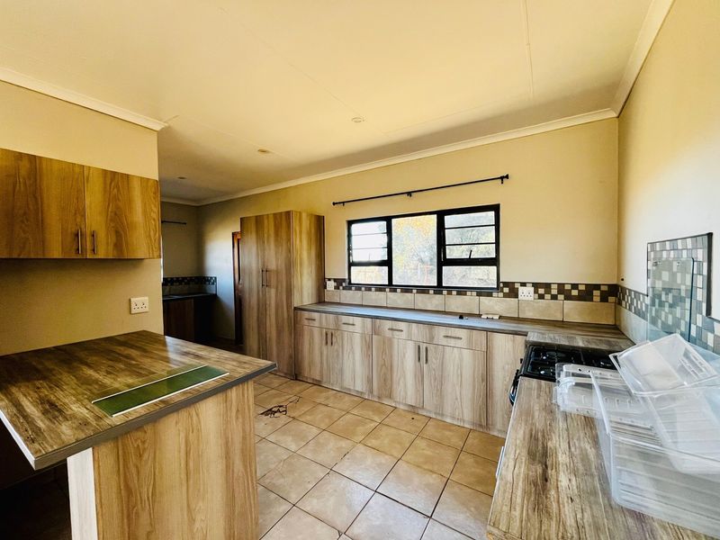 A functional kitchen featuring wood-look laminate cabinetry, tiled countertops, and a built-in gas hob, offering a clean and practical workspace.