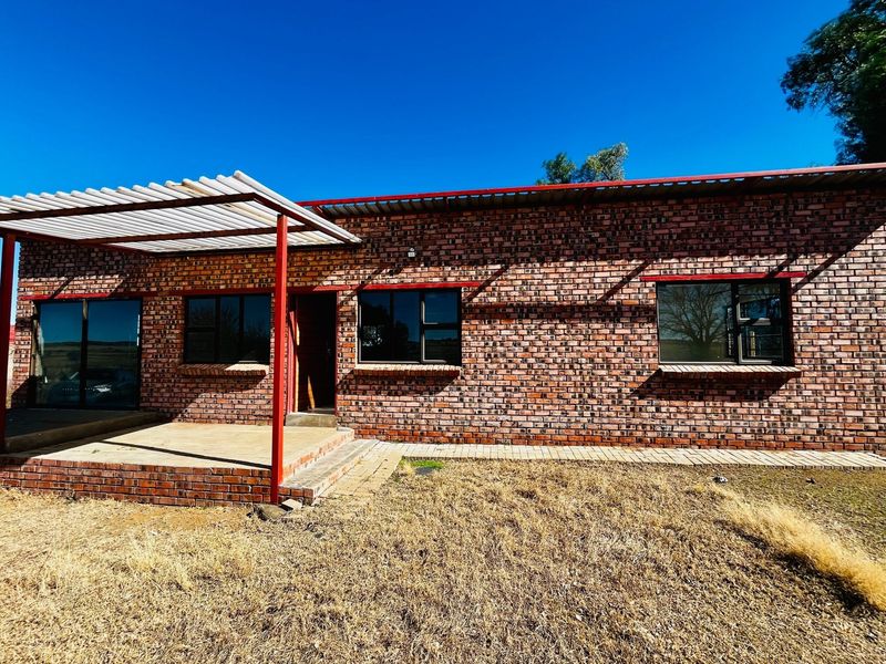 Rear exterior view of a townhouse featuring exposed brickwork, a covered patio area with a pergola, and aluminum-framed windows.