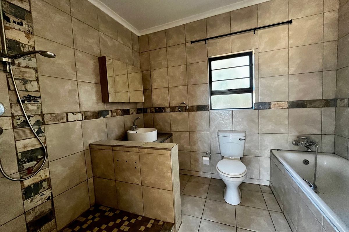 A dated bathroom featuring a shower, bathtub, toilet, and basin with tiled finishes, requiring some maintenance and cosmetic updates.