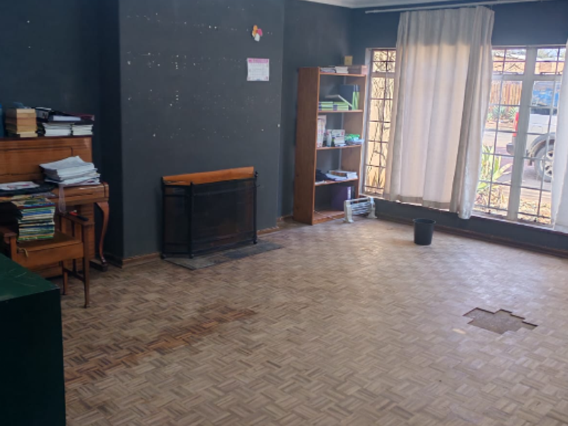 Living room featuring parquet flooring, a fireplace, and timber ceiling. The space requires floor repairs and cosmetic updates to improve its overall condition.