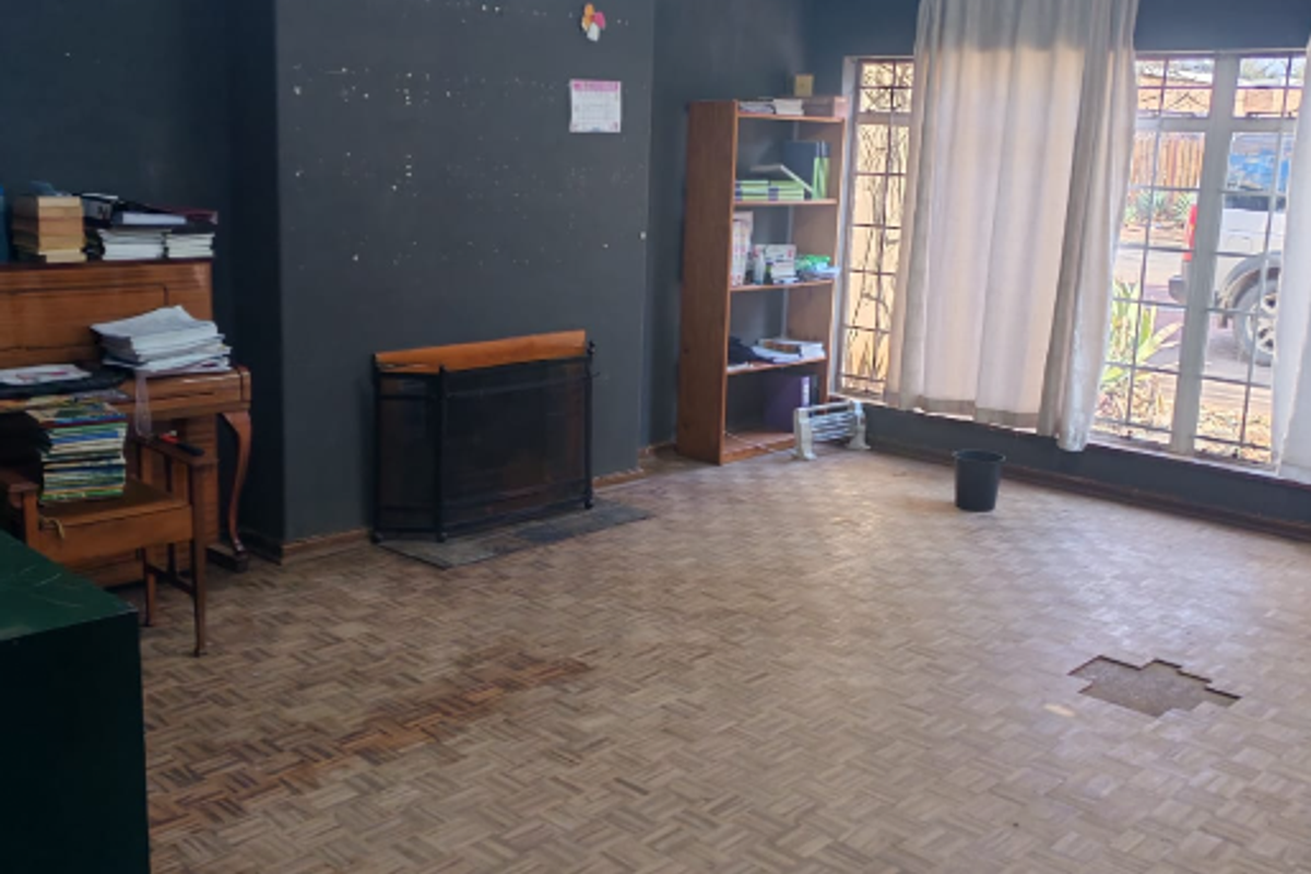 Living room featuring parquet flooring, a fireplace, and timber ceiling. The space requires floor repairs and cosmetic updates to improve its overall condition.