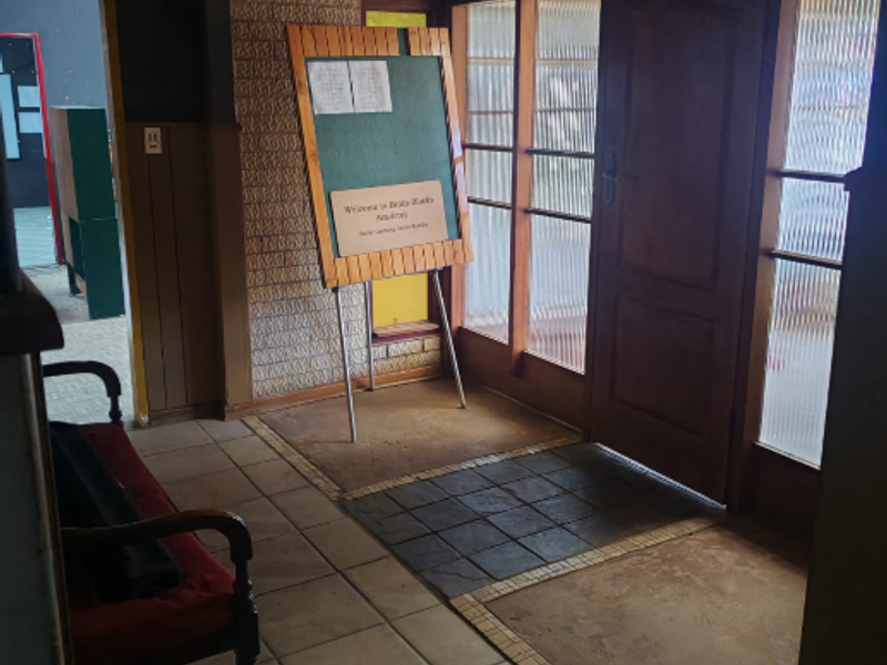 Entrance foyer featuring a timber-clad ceiling, textured brick feature wall, and tiled flooring, providing a dated but functional welcome area.