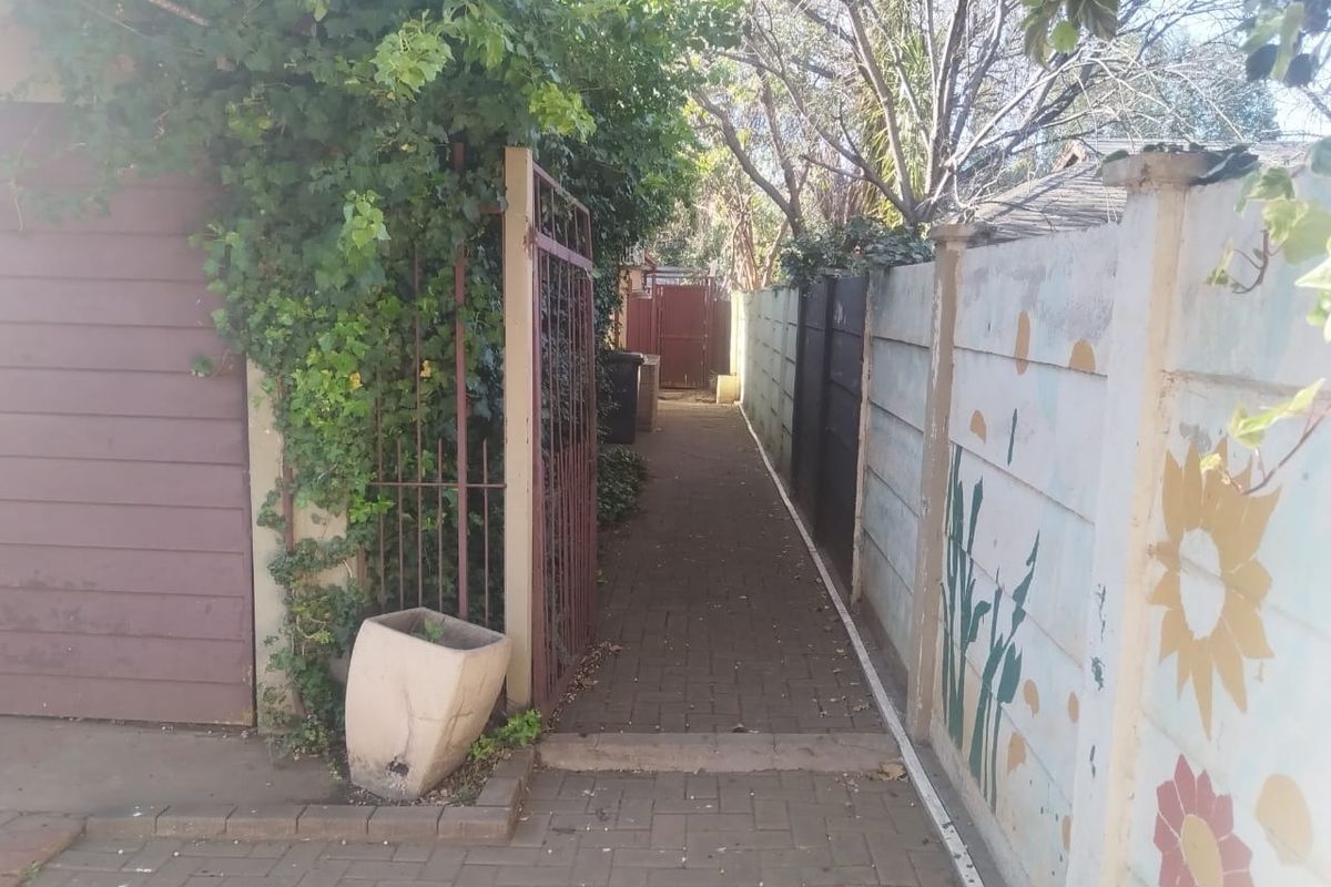 A narrow paved side walkway leading to the rear of the property, enclosed by a precast concrete boundary wall and metal gate.