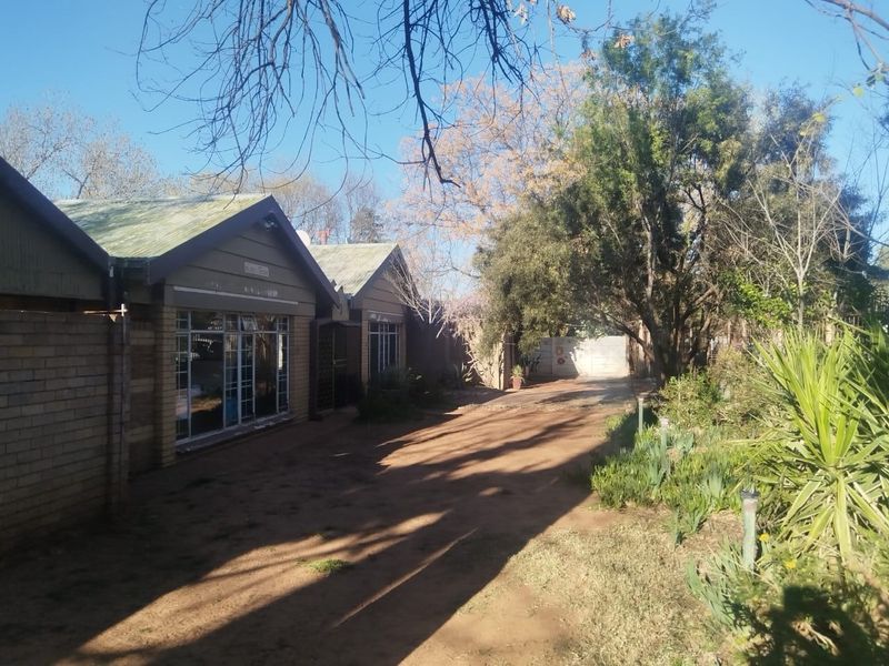 Front exterior view of a brick house featuring a pitched roof, aluminium windows, and a long driveway leading to the property entrance.