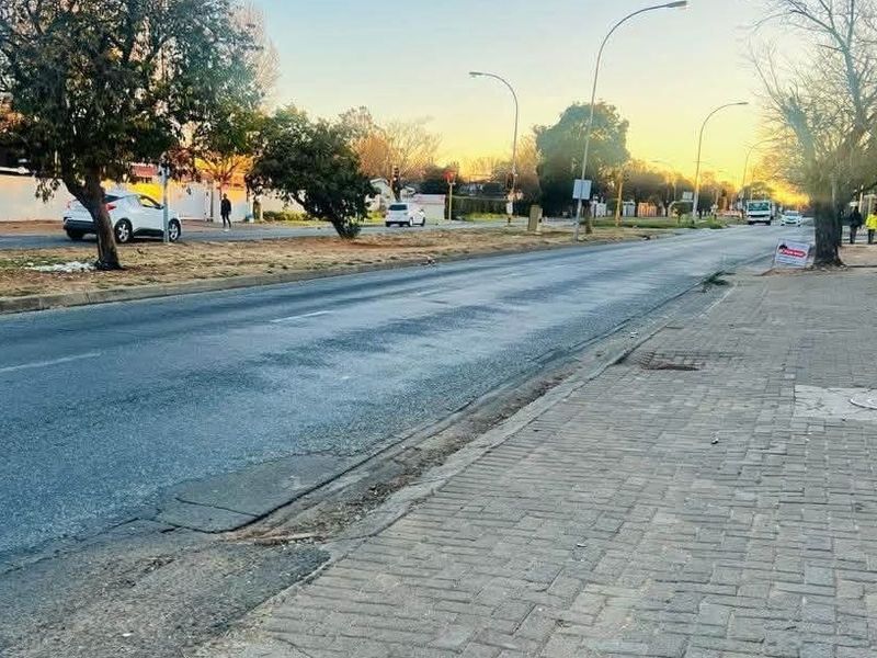 A view of the street and sidewalk adjacent to the property, featuring paved walkways and established street lighting.