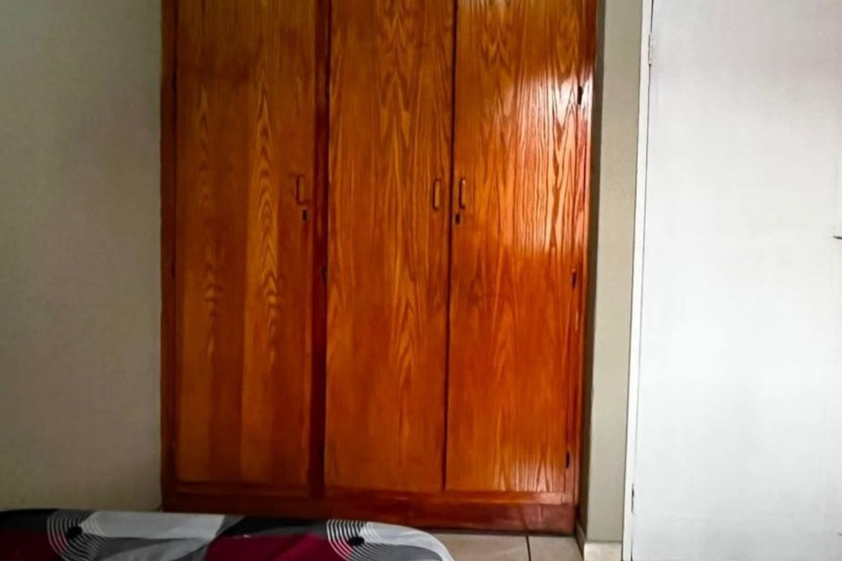 A bedroom featuring a large, built-in wooden wardrobe and a standard interior door.