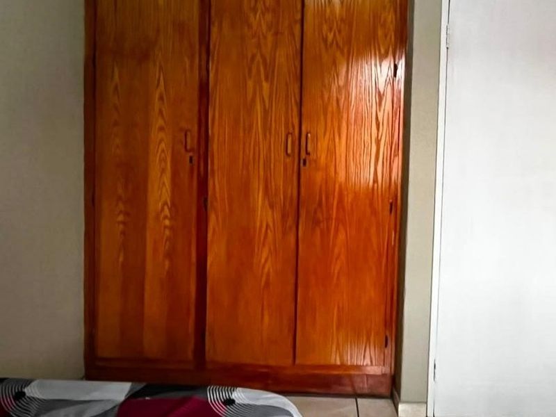 A bedroom featuring a large, built-in wooden wardrobe and a standard interior door.