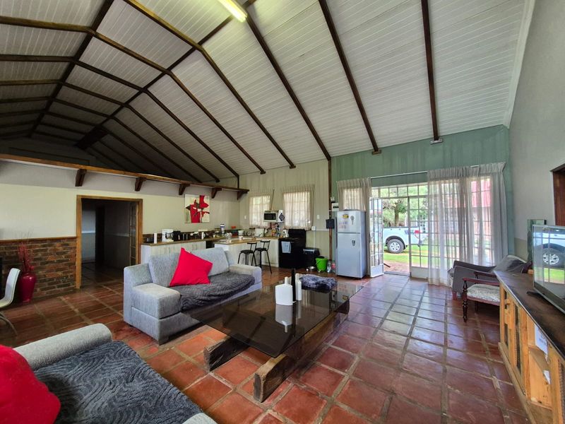Spacious open-plan living and kitchen area featuring a high vaulted timber ceiling, terracotta tile flooring, and direct access to the exterior.