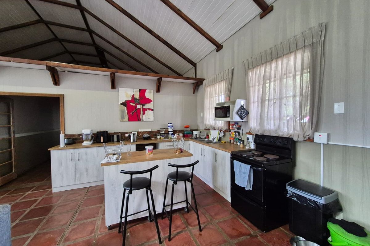 Open-plan kitchen featuring a central island, built-in cabinetry, electric stove, and a vaulted ceiling with exposed timber beams.