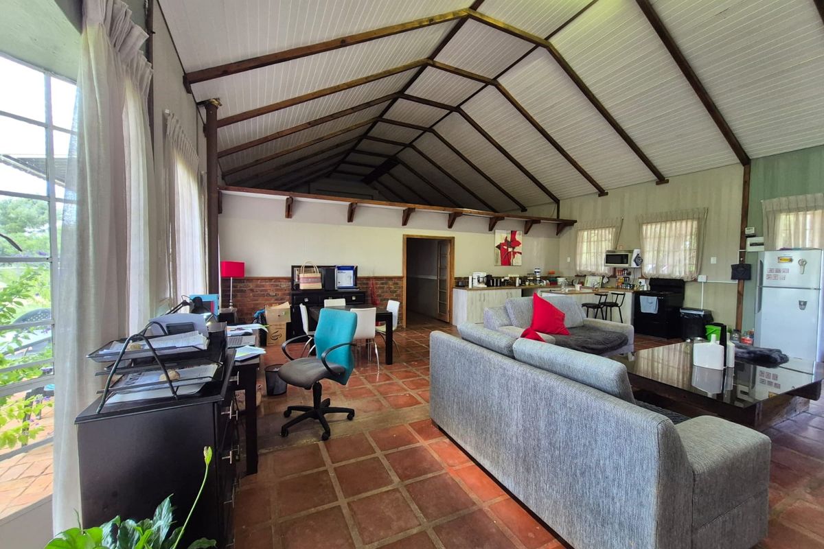 Spacious open-plan living and kitchen area featuring a high vaulted timber-beamed ceiling, terracotta tiled flooring, and exposed brick accents.