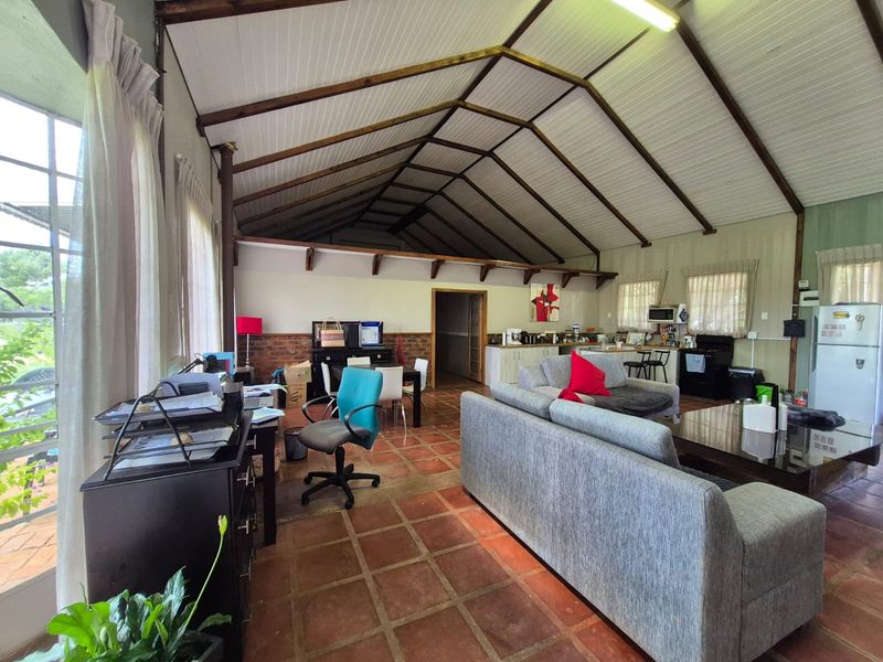 Spacious open-plan living and kitchen area featuring a high vaulted timber-beamed ceiling, terracotta tiled flooring, and exposed brick accents.