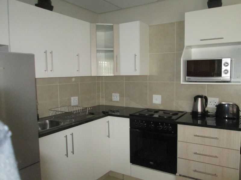 A functional kitchen featuring white cabinetry, dark granite countertops, a tiled backsplash, and a built-in electric stove with oven.