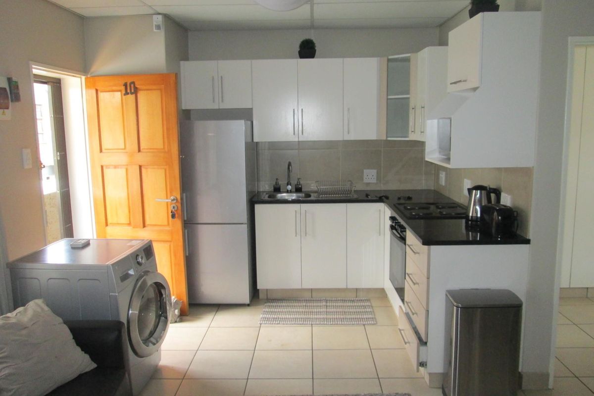 Compact kitchen featuring white cabinetry, dark countertops, built-in oven and hob, and tiled flooring, providing a functional workspace within the apartment.
