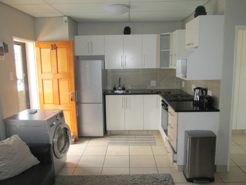 Compact kitchen featuring white cabinetry, dark countertops, built-in oven and hob, and tiled flooring, providing a functional workspace within the apartment.