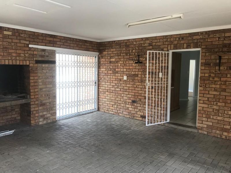Covered patio area featuring exposed brick walls, built-in braai, and brick paving, providing a functional outdoor entertainment space with direct access to the home.