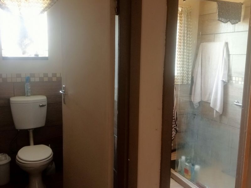 A functional bathroom featuring a separate toilet area and a shower enclosure with tiled wall finishes.