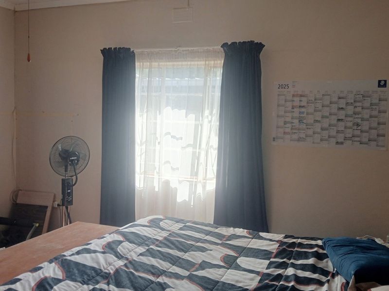 A standard bedroom featuring neutral walls, natural light through a window with curtain rails, and space for a double bed.